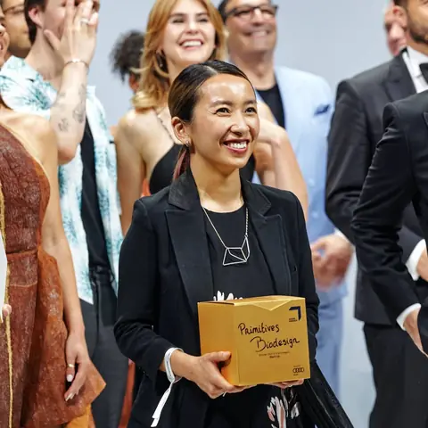 A GREEN AWARDS winner holding the trophy on the red carpet, 2021